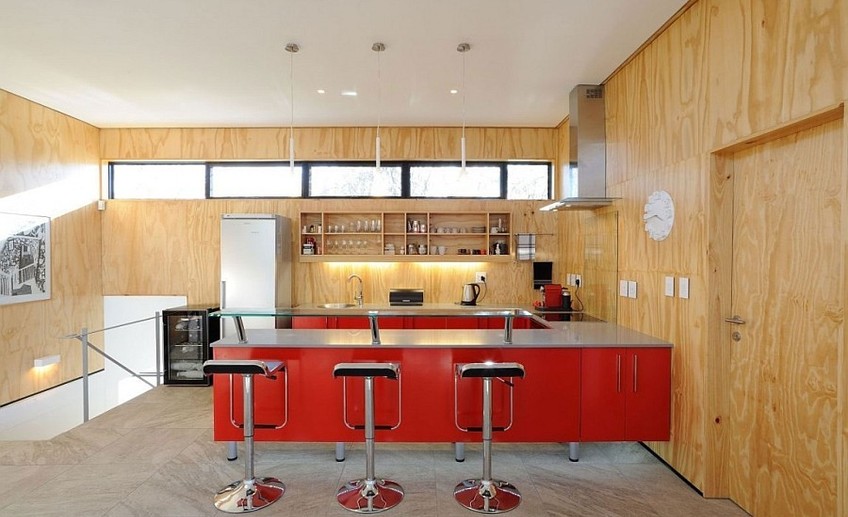 Usual lem piston bar stools and a ravishing red kitchen peninsula enliven the space