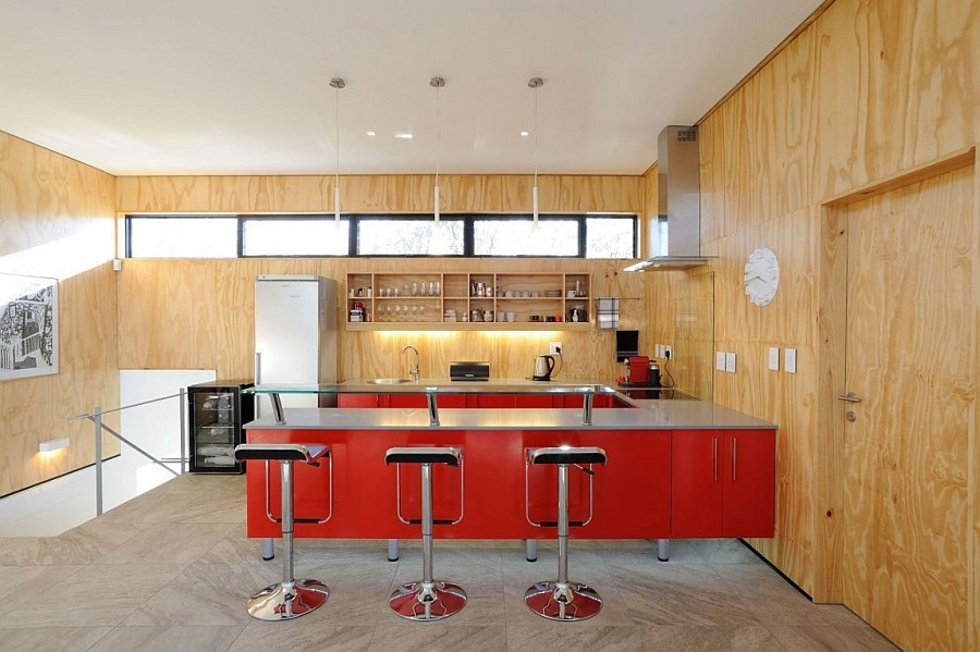 Lem piston bar stools and a ravishing red kitchen peninsula enliven the space